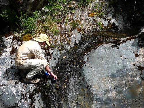 Filling a water bottle from a stream